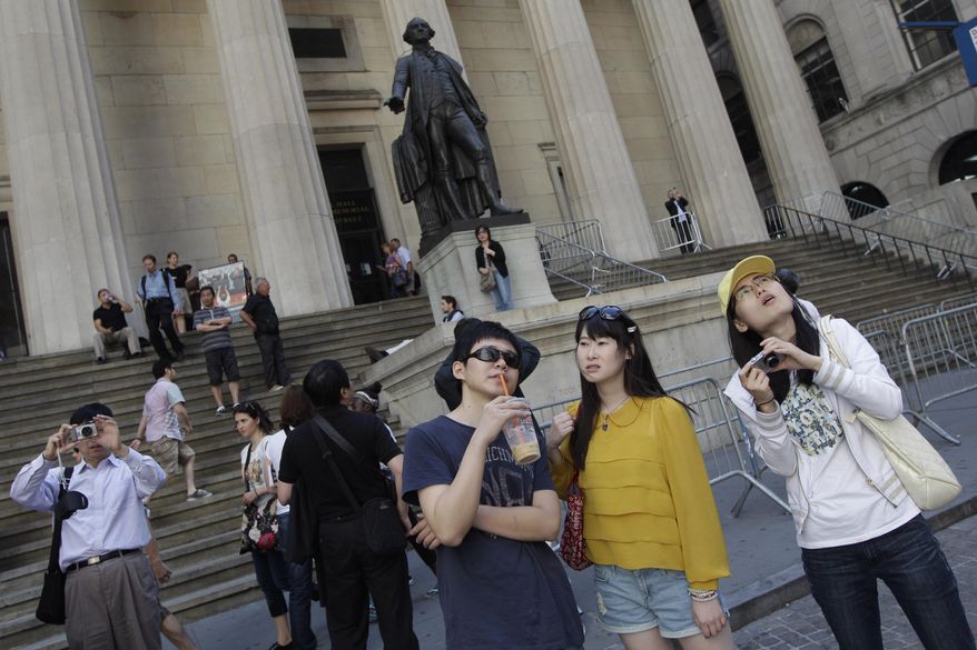 FILE - In this June 15, 2012, file photo, a group of tourists from China take in the sights of the New York Stock Exchange and Federal Hall National Memorial, in New York. Chinese tourists, already among the fastest-growing and highest-spending groups of international visitors to the United States, are poised to make an even bigger impact, thanks to a rule change that would allow visitors to get visas valid for 10 years. (AP Photo/Mary Altaffer, File)