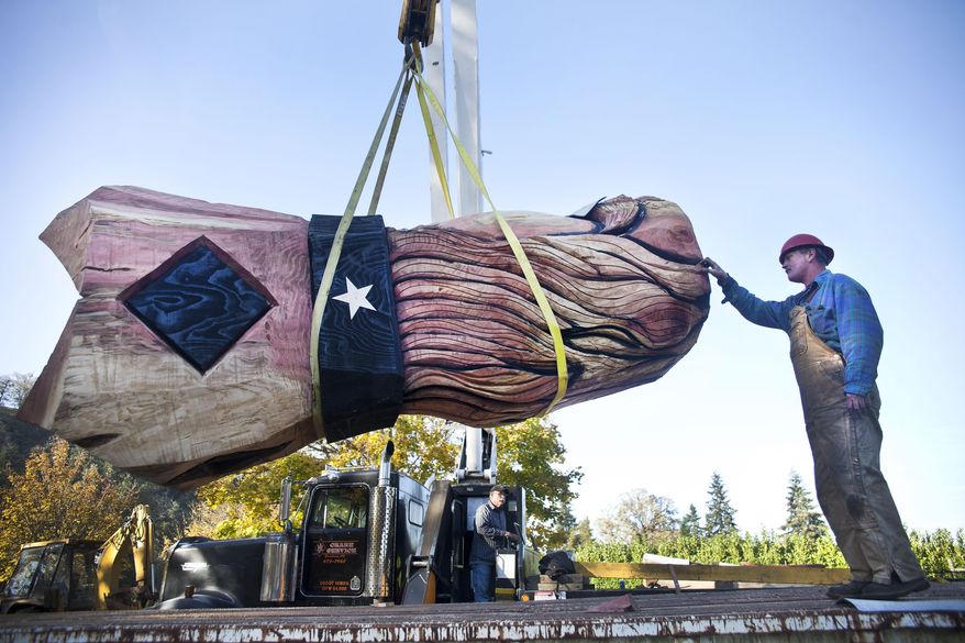 Mike Hackett, right, guides the head of the world's tallest wooden nutcracker for the Umpqua Valley Festival of Lights as Ron Covey lifts it off the trailer with a crane, Monday Nov. 17, 2014 in Roseburg, Ore. The 41-foot nutcracker was carved with chainsaws by Toby Johnson. (AP Photos/The News-Review, Katie Alaimo)