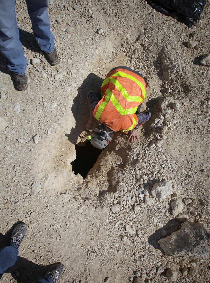 In this Sept. 7, 2012 photo, biologist Jean Krejca inspects a small cave uncovered by earthmoving equipment where Texas Department of Transportation was building an underpass along Texas 151 near Loop 1604 in San Antonio, Texas. Endangered spiders were found in the small feature, halting construction work as biologist study the rare spiders. (AP Photo/The San Antonio Express-News, Bob Owen) RUMBO DE SAN ANTONIO OUT; NO SALES