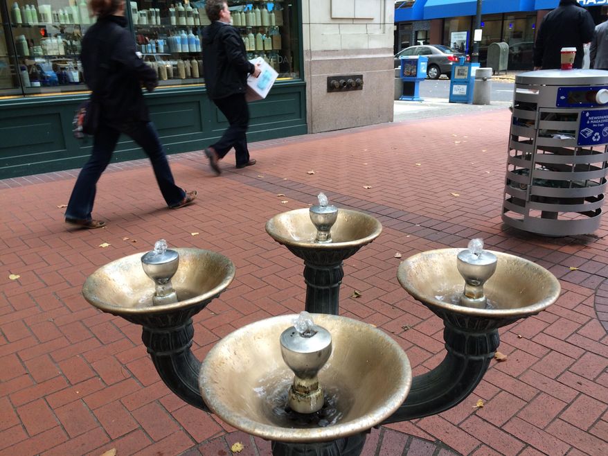 This Nov. 7, 2014 photo shows the first Benson Bubbler at the corner of Southwest Fifth and Washington in downtown Portland. Ore. Benson Bubblers are those brass, four-bowled water fountains that you can see scattered through the downtown core. Benson Bubblers go back to 1912, when Simon Benson donated $10,000 to the city (roughly $240,000 in today's money) to purchase and install 20 of the fountains. Engineers with the Water Bureau have struggled for decades with the question of how to balance the city's penchant for conservation with the sheer beauty of the fountains. (AP Photo/The Oregonian, John Killen) MAGS OUT; TV OUT; NO LOCAL INTERNET; THE MERCURY OUT; WILLAMETTE WEEK OUT; PAMPLIN MEDIA GROUP OUT