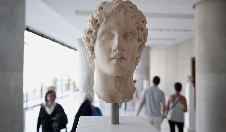 Visitors walk behind an ancient marble head of ancient Greek warrior-king Alexander the Great, displayed at the Acropolis museum in Athens, Oct. 12, 2014. Alexander the Great was one of the world&#39;s most successful military commanders, who enlarged his father&#39;s kingdom to include an empire stretching from modern Greece to India. During his youth, Alexander was tutored by the ancient Greek philosopher Aristotle until the age of 16. (AP Photo/Petros Giannakouris)