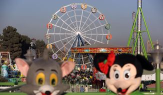 In this Friday, Nov. 14, 2014 photo, friendly characters that looklike Jerry the mouse from Tom and Jerry, left, and Minnie Mouse welcome visitors at Afghanistan&#39;s first amusement park called City Park in Kabul. Excitement builds in the queue forming behind the barbed-wire security fence outside the park as children in bright clothes clutch their parents&#39; hands and hop from foot to foot in anticipation of the pleasures waiting behind the high concrete blast walls. For the thousands of families who have visited there since it opened during a national religious holiday weekend in October, it is a rare escape from lives blighted by war, death and misery. (AP Photo/Rahmat Gul)