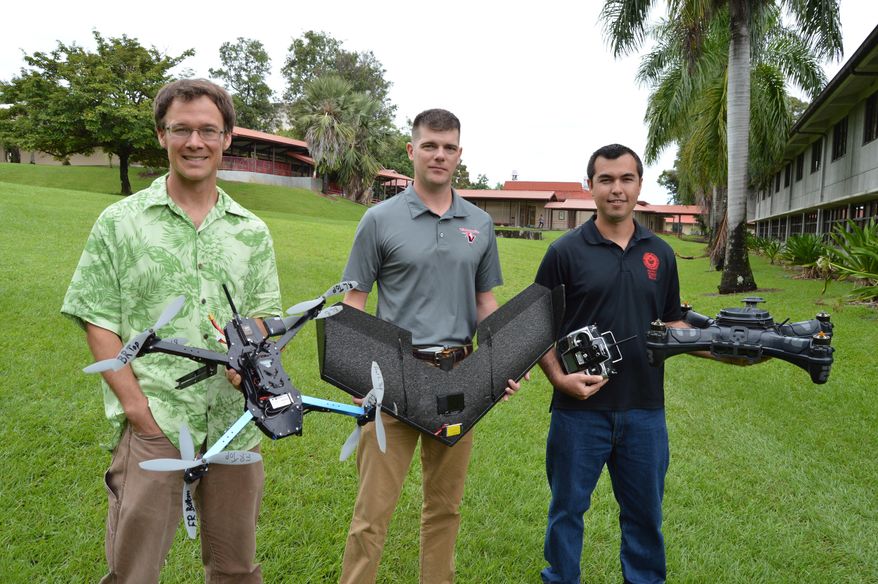 This photo taken Nov. 19, 2014, in Hilo, Hawaii, shows University of Hawaii at Hilo researchers Ryan Perroy, left, Arthur Cunningham, middle, and Nicolas Turner, right, display some of their unmanned aerial vehicles they use on their flight team with the UH-Hilo Spatial Data Analysis and Visualization Laboratory. The team has been working to map the June 27 lava flow as it continues to impact the lower Puna area. (AP Photo/ Hawaii Tribune-Herald, Colin Stewart)