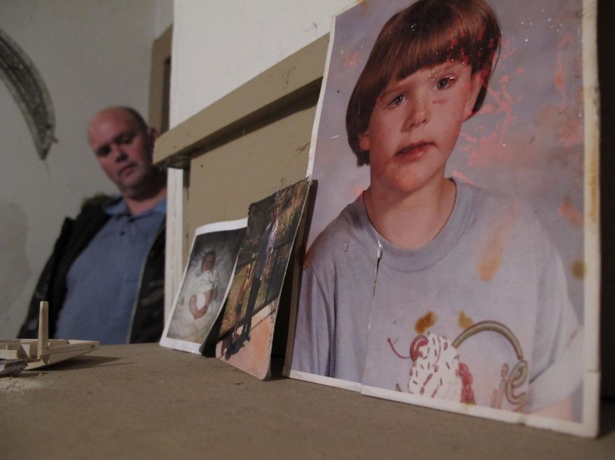 ADVANCE FOR USE THURSDAY, NOV. 27, AND THEREAFTER- In this Oct. 31, 2014, photo, Scotty Reynolds, left, peeks around a corner at childhood photos of himself in Lexington, N.C. Separated from his parents at a young age and sent to group homes, the mentally disabled man, with help from his "guardian angel" and members of the community, is now poised to have a home of his own. (AP Photo/Allen G. Breed)