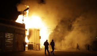People walk away from a storage facility on fire after the announcement of the grand jury decision Monday, Nov. 24, 2014, in Ferguson, Mo. A grand jury has decided not to indict Ferguson police officer Darren Wilson in the death of Michael Brown, the unarmed, black 18-year-old whose fatal shooting sparked sometimes violent protests. (AP Photo/Jeff Roberson)