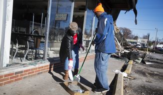 Sharon Otis, left, and her son Jonathan Johnson, 16, both of Ferguson, Mo., help clean up a strip mall after it was damaged in last night&#39;s riots, Tuesday, Nov. 25, 2014, in Ferguson, Mo. (AP Photo/David Goldman)
