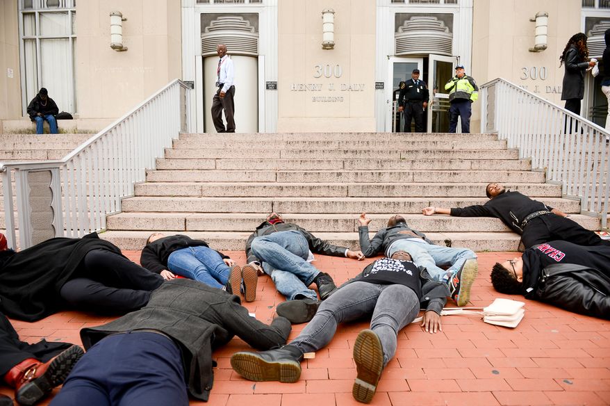Members of the DC chapter of the Black Youth Project 100 (BYP100) participate in a "Die-In" on the steps of the Washington, D.C. Metropolitan Police Department headquarters at 300 Indiana Avenue, NW after a Grand Jury’s decision to not indict Ferguson police officer Darren Wilson in the killing of 18 year-old Michael Brown, Washington, D.C., Tuesday, November 25, 2014. The non-violent protest was part of a 28 hour long series of protests "aimed at bringing an end to the cycle of state sanction violence against local black communities carried out by the police." (Andrew Harnik/The Washington Times)
