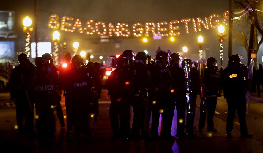 Police in riot gear use tear gas to clear the street in front of the Ferguson Police Department after the announcement of the grand jury decision not to indict police officer Darren Wilson in the fatal shooting of Michael Brown, an unarmed black 18-year-old, Monday, Nov. 24, 2014, in Ferguson, Mo. (AP Photo/Charlie Riedel)