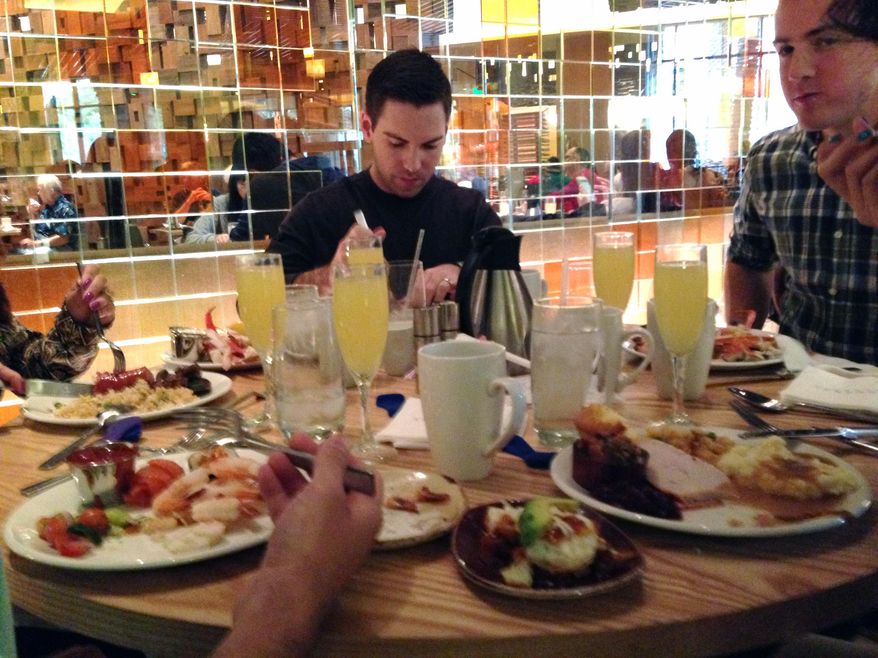 Josh Wells, 32, of Oklahoma City sits at a table with family and friends eating an unconventional Thanksgiving feast at the Bacchanal Buffet at Caesars Palace in Las Vegas on Thursday, Nov. 27, 2014. Vegas visitors lined up Thursday before noon for a chance to pile plates high for an unconventional holiday on the Strip. (AP Photo/Kimberly Pierceall)
