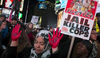 In this Nov. 25, 2014, file photo, demonstrator Maryam Said in New York raises her painted hands during a protest against a grand jury&#39;s decision on Monday not to indict Ferguson Police Officer Darren Wilson in the shooting of Michael Brown. (AP Photo/John Minchillo, File)