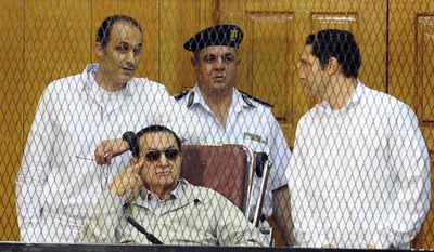 Former Egyptian President Hosni Mubarak, seated, and his two sons Gamal Mubarak, left, and Alaa Mubarak, right, attend a hearing in a courtroom at the Police Academy, Cairo, Egypt, in this Sept. 14, 2013, file photo. (AP Photo/Ahmed Omar, File)
