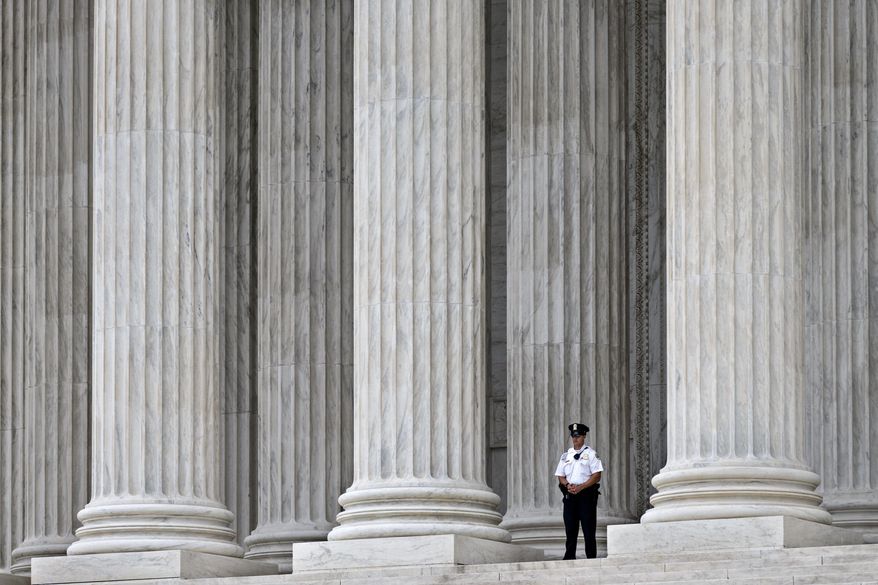 FILE - This Oct. 7, 2014, file photo shows a police officer dwarfed amid the marble columns of the U.S. Supreme Court in Washington. Anthony Elonis claimed he was just kidding when he posted a series of graphically violent rap lyrics on Facebook about killing his estranged wife, shooting up a kindergarten class and attacking an FBI agent. But his wife didn't see it that way. Neither did a federal jury. In a far-reaching case that probes the limits of free speech over the Internet, the Supreme Court on Monday is considering whether Elonis' Facebook posts, and others like it, deserve protection under the First Amendment. (AP Photo/J. Scott Applewhite, File)