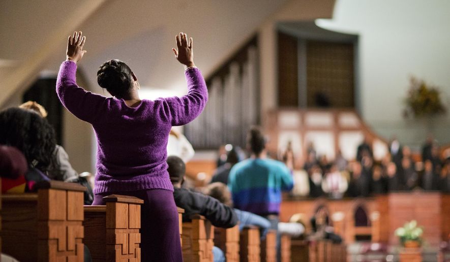 A woman raises her hands as the choir sings before U.S. Attorney General Eric Holder speaks to members of the community during an interfaith service at Ebenezer Baptist Church, the church where The Rev. Martin Luther King Jr. preached, Monday, Dec. 1, 2014, in Atlanta. Holder traveled to Atlanta to meet with law enforcement and community leaders for the first in a series of regional meetings around the country. The president asked Holder to set up the meetings in the wake of clashes between protesters and police in Ferguson, Missouri. (AP Photo/David Goldman)