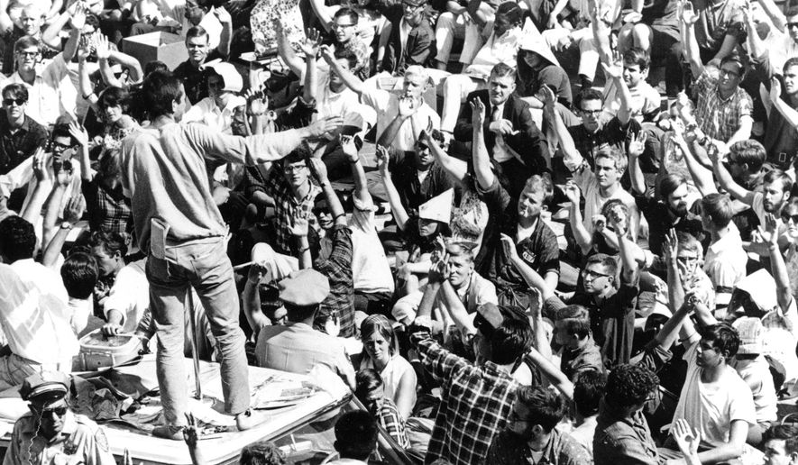 FILE - In this Oct. 2, 1964 file photo, standing atop the crushed roof of a campus police car, a University of California student asks Cal students to identify themselves during third day of Free Speech Movement demonstrations in Berkeley, Calif. One student has been arrested and confined in the police car which is surrounded by the demonstrators. The fall of 2014 marks the 50th anniversary of the Free Speech Movement, a protest that only lasted for three months but set the stage for the turbulent 1960s. (AP Photo, File)