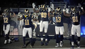 Members of the St. Louis Rams raise their arms in awareness of the events in Ferguson, Mo.,  as they walk onto the field during introductions before an NFL football game against the Oakland Raiders, Sunday, Nov. 30, 2014, in St. Louis.  The players said after the game, they raised their arms in a &amp;quot;hands up&amp;quot; gesture to acknowledge the events in Ferguson. (AP Photo/L.G. Patterson)