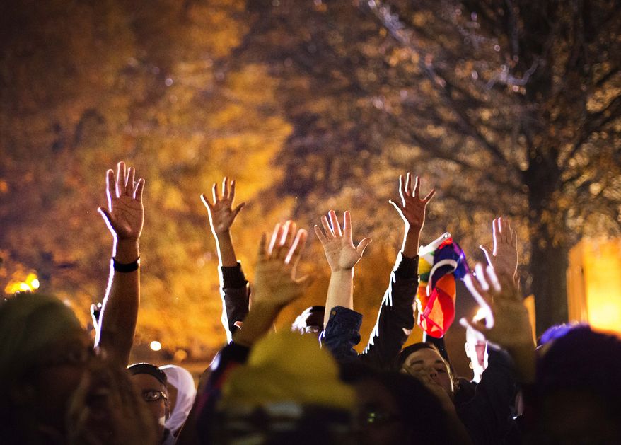 Protesters hold up their hands while chanting "hands up don't shoot" outside Ebenezer Baptist Church, the church where The Rev. Martin Luther King Jr. preached, as U.S. Attorney General Eric Holder speaks inside to members of the community during an interfaith service, Monday, Dec. 1, 2014, in Atlanta. Holder traveled to Atlanta to meet with law enforcement and community leaders for the first in a series of regional meetings around the country. The president asked Holder to set up the meetings in the wake of clashes between protesters and police in Ferguson, Missouri. (AP Photo/David Goldman)