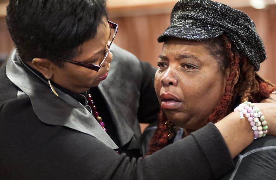 Dell Taylor, right, is comforted by the Rev. Traci Blackmon, a member of the Ferguson Commission appointed by Missouri Gov. Jay Nixon, during the opening meeting of the commission at the Ferguson Community Center in Ferguson, Mo. Monday, Dec. 1, 2014. The 16-person panel was chosen by Missouri's governor to help find long-term solutions after the Ferguson police shooting of an unarmed man. (AP Photo/Sid Hastings)