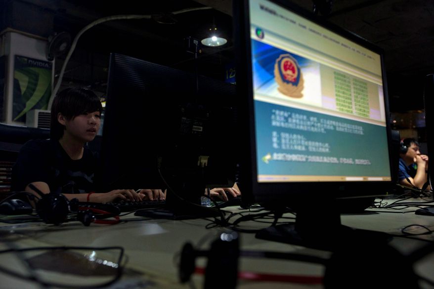 Computer users sit near a display with a message from the Chinese police on the proper use of the Internet at an Internet cafe in Beijing, China, in this Aug. 19, 2013, file photo. (AP Photo/Ng Han Guan, File)
