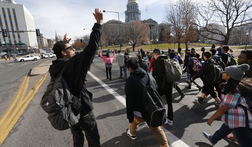 East High School students march in a protest against the Ferguson, Missouri grand jury decision, along a busy street in front of the state Capitol in Denver, Wednesday Dec. 3, 2014. Authorities said four Denver police officers were hit by a car while watching the high school students protest.   (AP Photo/Brennan Linsley)