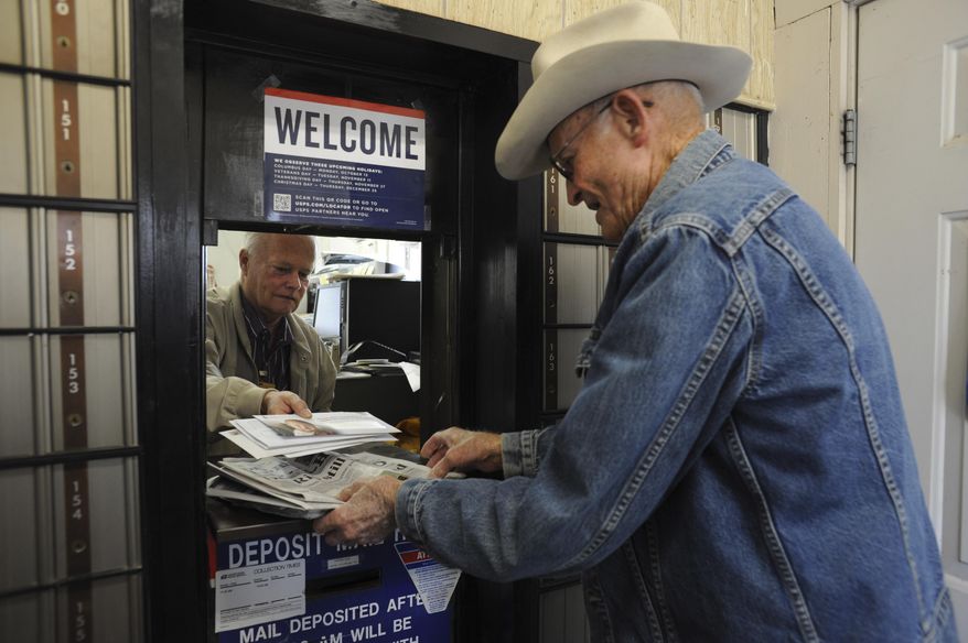 Jackie Skiles, 83, picks up his mail from postmaster Neal Wellman in Langtry, Texas, on Friday, Nov. 21, 2014. Skiles is one of the very residents still living in Langtry. Once a bustling railroad and ranching hub an hour west of Del Rio, Langtry now is little more than a collection of empty homes and crumbling ruins, reduced to five families, a highway gas station and the state visitors center. (AP Photo/The San Antonio Express-News, Billy Calzada) RUMBO DE SAN ANTONIO OUT; NO SALES