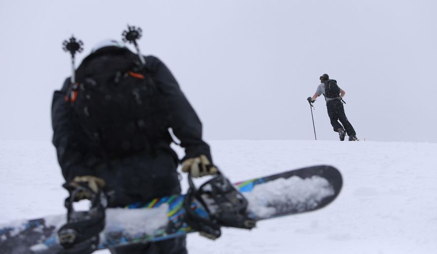 ADVANCE FOR WEEKEND EDITIONS, DEC 6-7 - In this photo taken on Nov. 21, 2014, Luke Fortezzo, foreground, and Luke Bates, rear, both from Bend, Ore., hike up the cinder cone at Mount Bachelor Ski Area about 20 miles west of Bend, Ore. Hiking and riding the cone are sort of preseason traditions in Central Oregon before the ski area begins its chairlift operations for the season. When the region was blasted with early-season snow over the last couple of weeks, snowriders flocked to the cone, which is easily accessible from the Bachelor parking lot. (AP Photo/The Bulletin, Joe Kline)