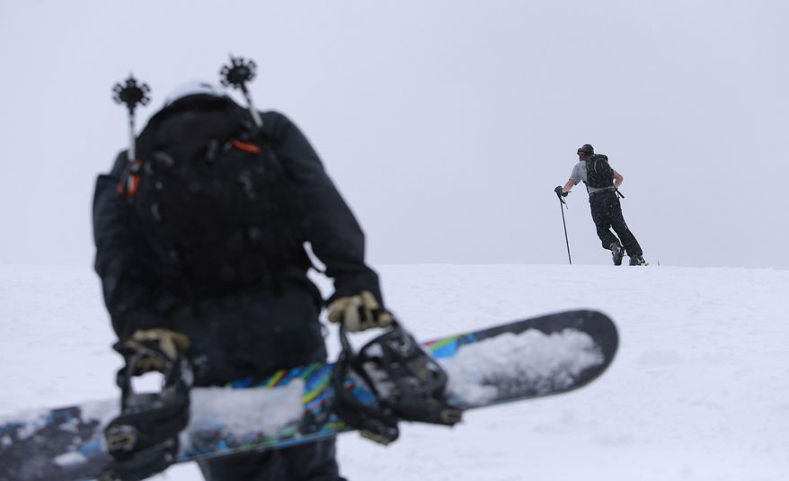 ADVANCE FOR WEEKEND EDITIONS, DEC 6-7 - In this photo taken on Nov. 21, 2014, Luke Fortezzo, foreground, and Luke Bates, rear, both from Bend, Ore., hike up the cinder cone at Mount Bachelor Ski Area about 20 miles west of Bend, Ore. Hiking and riding the cone are sort of preseason traditions in Central Oregon before the ski area begins its chairlift operations for the season. When the region was blasted with early-season snow over the last couple of weeks, snowriders flocked to the cone, which is easily accessible from the Bachelor parking lot. (AP Photo/The Bulletin, Joe Kline)