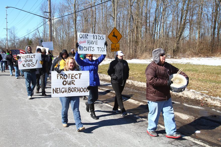 This Feb. 22, 2014 photo shows residents marching on Leydecker Road in West Seneca, N.Y. to protest against a group home for sex offenders in the neighborhood. The state's placement of six convicted sex offenders at adjoining group homes for the disabled in suburban Buffalo has upset neighbors. The Office for People with Developmental Disabilities says the men were moved from a Rochester facility in the statewide plan to move people from institutions to community-based programs. (AP Photo/The Buffalo News, John Hickey)
