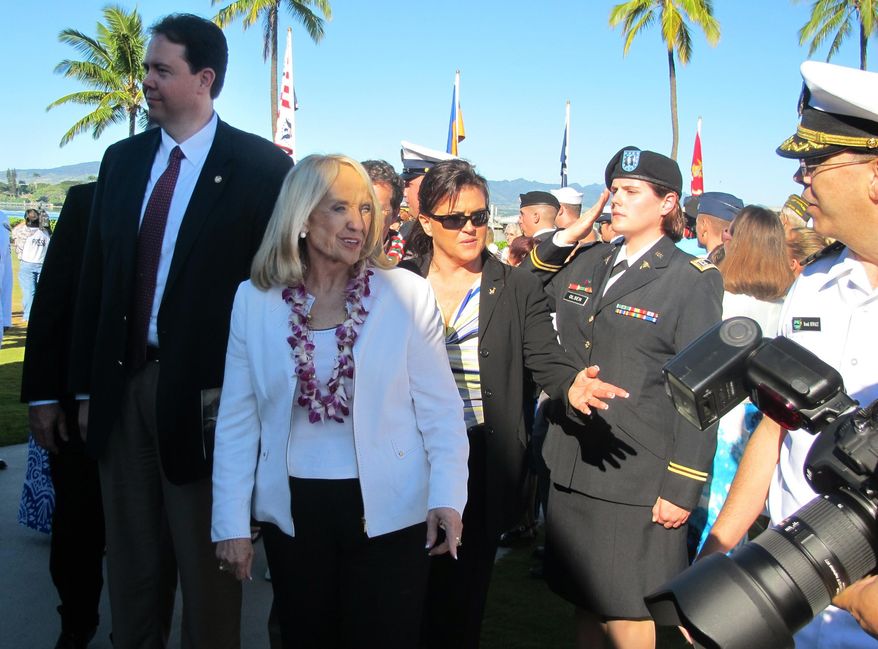 Arizona Gov. Jan Brewer, center, is surrounded by unidentified officials as she attends the 73rd anniversary ceremony of the attack on Pearl Harbor, in Hawaii on Sunday, Dec. 7, 2014. Gov. Brewer toured the memorial of the sunken battleship USS Arizona and then make a visit to a modern warship named for an Arizona city, the attack submarine USS Tucson. (AP Photo/Jennifer Sinco Kelleher)