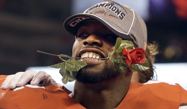 Ohio State cornerback Doran Grant holds a rose in his teeth after the Buckeyes 59-0 victory over Wisconsin in the Big Ten Conference championship NCAA college football game after midnight Sunday, Dec. 7, 2014, in Indianapolis. Ohio State won 59-0. (AP Photo/Darron Cummings)