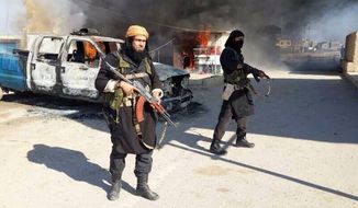 This undated file image posted on a militant website on Jan. 4, 2014, which is consistent with other AP reporting, shows Shakir Waheib, a senior member of the Islamic State of Iraq and the Levant (ISIL), now called the Islamic State group, left, next to a burning police vehicle in Iraq&#39;s Anbar Province. (AP Photo via militant website, File)