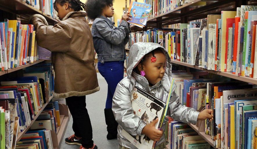 In this Wednesday , Nov. 26, 2014 photo, Sisters Yasmin Ousley, 10, left, Corionna King, 12 and Keiris Ousley, 3, look for books at the Ferguson Municipal Public Library in Ferguson, Mo. The Ferguson Municipal Public Library has received more than $350,000 in donations and gifts of books that will keep the library cataloger busy for some time. Contributions have soared since Nov. 24, when the library decided to stay open despite protests over a grand jury's decision to not indict officer Darren Wilson in the death of Michael Brown. (AP Photo/St. Louis Post-Dispatch, J.B. Forbes) EDWARDSVILLE INTELLIGENCER OUT; THE ALTON TELEGRAPH OUT
