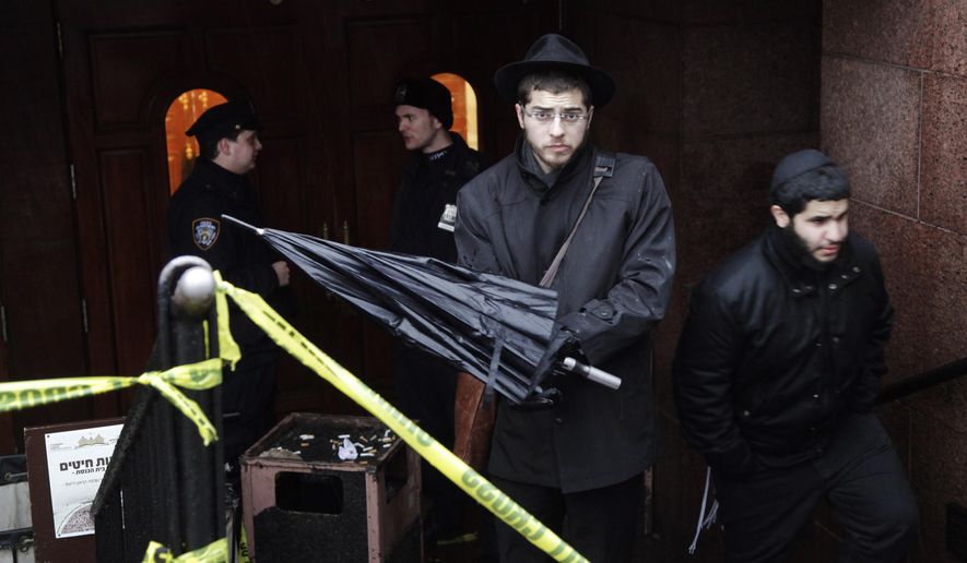 A member of the Lubavitch community, center, leaves the Chabad-Lubavitch Hasidic headquarters guarded by members of the New York Police Department, left, Tuesday, Dec. 9, 2014, in New York. A knife-wielding man stabbed an Israeli student inside the Brooklyn synagogue before being fatally shot by police after he refused to drop the knife. The student, Levi Rosenblatt, is in stable condition. (AP Photo/Mark Lennihan)