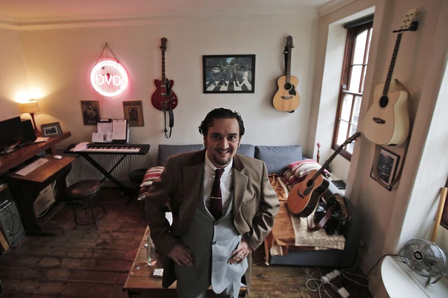 On this Friday, Dec. 5, 2014 photo, musician Tim Arnold, poses in his flat in central London's Soho district. The closure of Madame Jojo's, the venerable burlesque nightclub has ignited a battle between developers, locals and entertainers for the soul of Soho, the city's late-night hub, red-light district and creative heart. Arnold has enlisted friends and fellow performers to try and reverse the closure. (AP Photo/Lefteris Pitarakis)