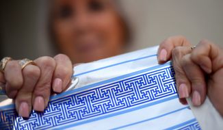 Cheryl Shapiro displays the Hanukkah gift wrap with a swastika-like pattern she found at Walgreens in Northridge, Calif., Monday, Dec. 8, 2014.  The wrapping paper has been recalled from stores nationwide. (AP Photo/Los Angeles Daily News, Andy Holzman)