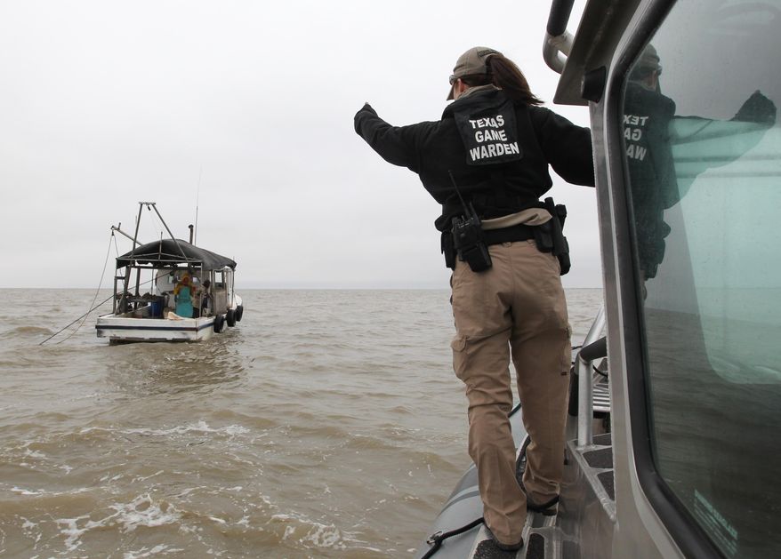 In this Tuesday Dec. 2, 2014 photo, Texas Parks and Wildlife Game Warden Jennifer Provaznik yells instructions to an oyster boat captain, in East Galveston Bay, Texas. State officials have recommended parts of Galveston Bay be closed to oyster harvesting amid concerns over immature mollusks being removed and reefs still recovering from 2008’s Hurricane Ike. (AP Photo/The Galveston County Daily News, Jennifer Reynolds) ** MANDATORY CREDIT, NO SALES, MAGS OUT, TV OUT **