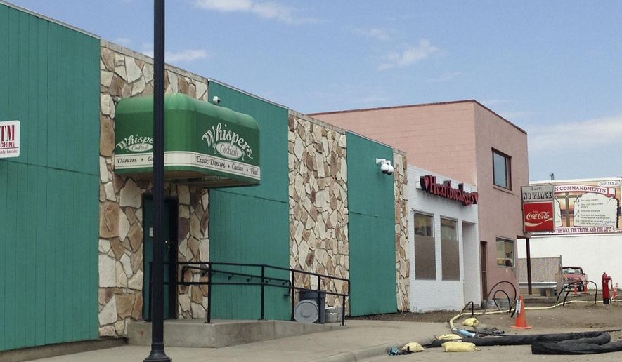 FILE - This Aug. 11, 2014 file photo shows two strip clubs along Main Street in Williston, N.D. Williston commissioners voted unanimously Tuesday night, Dec. 9, 2014, to suspend the liquor licenses of the city's two strip clubs for the second time in two years due to what police say are an excessive number of complaints about disorderly behavior. (AP Photo/Josh Wood, File)
