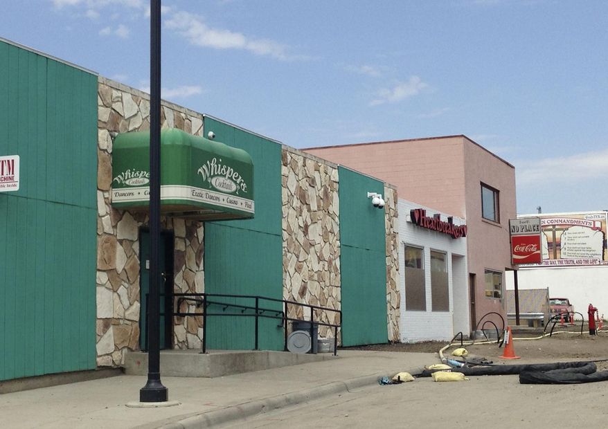 FILE - This Aug. 11, 2014 file photo shows two strip clubs along Main Street in Williston, N.D. Williston commissioners voted unanimously Tuesday night, Dec. 9, 2014, to suspend the liquor licenses of the city's two strip clubs for the second time in two years due to what police say are an excessive number of complaints about disorderly behavior. (AP Photo/Josh Wood, File)