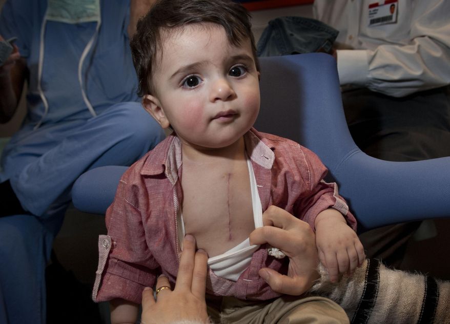 In a Monday, Dec. 8, 2014 photo, Daniel Alpatros, 1, is examined at Helen DeVos Children's hospital in Grand Rapids, Mich. The Iraqi boy was brought here by Healing the Children for successful heart surgery that was performed by Dr. Marcus Haw on Nov, 11. Daniel's parents now have hope for a long and active life for him. (AP Photo/The Grand Rapids Press, Chris Clark) ALL LOCAL TELEVISION OUT; LOCAL TELEVISION INTERNET OUT