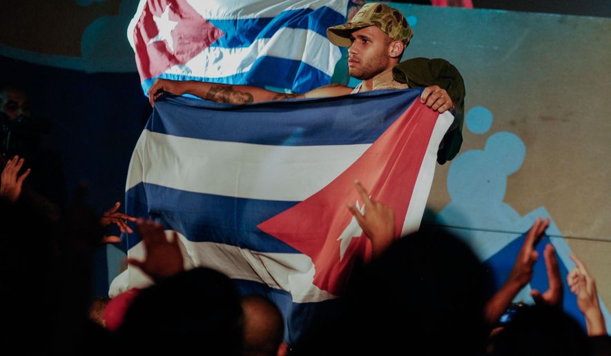 In this April 23, 2010, photo, Cuban singer Bian Rodriguez, member of Los Aldeanos, holds a Cuban flag as they play in concert at the Acapulco Theater in Havana, Cuba. Documents obtained by The Associated Press show that a U.S. agency infiltrated Cuba's hip-hop scene, recruiting unwitting rappers to spark a youth movement against the government. (AP Photo)