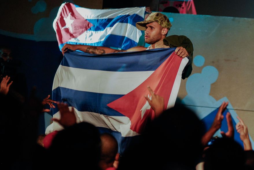 In this April 23, 2010, photo, Cuban singer Bian Rodriguez, member of Los Aldeanos, holds a Cuban flag as they play in concert at the Acapulco Theater in Havana, Cuba. Documents obtained by The Associated Press show that a U.S. agency infiltrated Cuba's hip-hop scene, recruiting unwitting rappers to spark a youth movement against the government. (AP Photo)