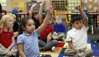 Ella Perez, left, and Christian Sliva-Pedroz raise their hands to answer a question as student teacher Josh Wieder reads to the students in Bethany Farrell&#39;s kindergarten class on Nov. 5, 2014, at Miller Elementary School in Lafayette, Ind. (AP Photo/Journal &amp;amp; Courier, John Terhune) ** FILE **