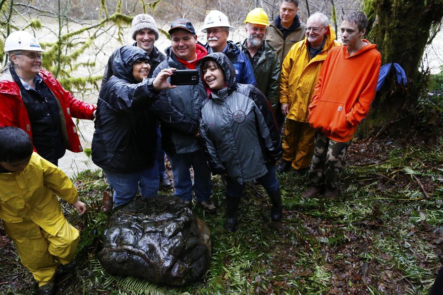 In a Wednesday, Dec. 10, 2014 photo, Quileute tribal members and state Department of Natural Resources archaeologists pose for a selfie after a ceremony to celebrate the the discovery of a rock that appears to be a carving that depicts a legendary battle in Quileute mythology, according to tribal and state officials. State archaeologists authenticated the carving and think it may date to around or before the mid-1700s. (AP Photo/The Seattle Times, Mark Harrison) SEATTLE OUT; USA TODAY OUT; MAGS OUT; TELEVISION OUT; NO SALES; MANDATORY CREDIT TO BOTH THE SEATTLE TIMES AND THE PHOTOGRAPHER