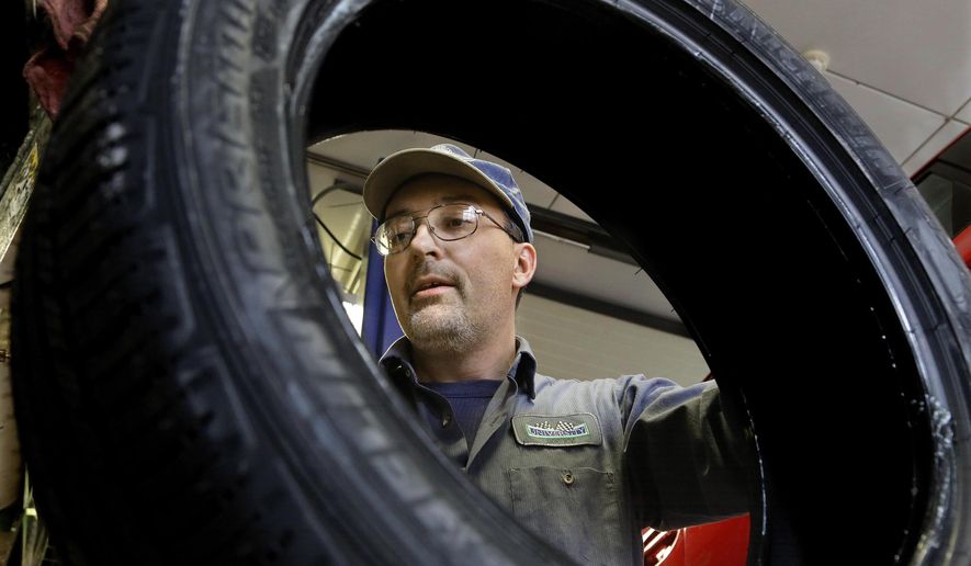 ADVANCE FOR SATURDAY DEC. 13 AND THEREAFTER-John Phillips Jr. works at his auto repair shop Thursday, Dec. 11, 2014, in Decatur, Ill. Phillips decided to stick with the same Blue Cross Blue Shield policy even though their monthly premiums will increase slightly to $249 a month after their tax credit. (AP Photo/Seth Perlman)