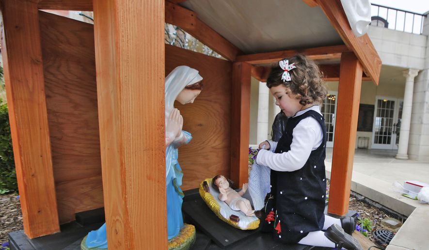 Gloria Harrigill, 3, places a blanket on a statue of baby Jesus on a Nativity scene at the Governor&#39;s Mansion in Oklahoma City, Friday, Dec. 12 2014. The Nativity Committee of Tulsa and Knights of Columbus provided the Nativity Scene that will be displayed over the Christmas holiday.  (AP Photo/The Oklahoman, Steve Gooch) 