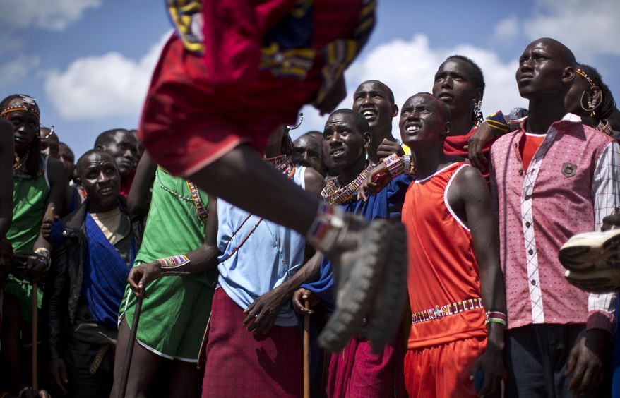 Maasai warriors look up as a competitor makes the high jump, in which athletes must touch a high line with the top of their heads, at the annual Maasai Olympics in the Sidai Oleng Wildlife Sanctuary near to Mt. Kilimanjaro, southern Kenya, Saturday, Dec. 13, 2014. Maasai men and women from the Amboseli and Tsavo region compete for medals and prizes in the event which aims for a sports competition of Maasai skills such as running, jumping, and throwing, to replace lion-hunting as the traditional warrior activity. (AP Photo/Ben Curtis)