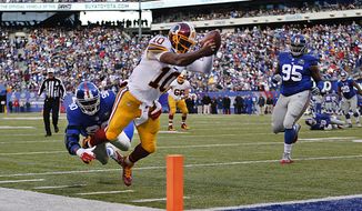 Washington Redskins quarterback Robert Griffin III (10) leaps for the goal line attempting to score a touchdown against New York Giants defensive end Jason Pierre-Paul (90) during the second quarter of an NFL football game, Sunday, Dec. 14, 2014, in East Rutherford, N.J. (AP Photo/Julio Cortez) 