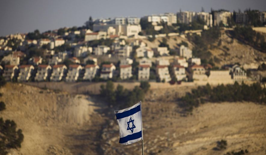 FILE - In this Monday, Sept. 7, 2009 file photo, an Israeli flag is seen in front of the West Bank Jewish settlement of Maaleh Adumim on the outskirts of Jerusalem. The population of Jewish settlers in the occupied West Bank has surged during Prime Minister Benjamin Netanyahu's years in office, growing at more than twice the pace of the overall population, according to official figures obtained in December, 2014. (AP Photo/Bernat Armangue, File)