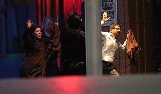 Hostages run to safety  during a cafe siege in the central business district of Sydney , Australia, Tuesday, Dec. 16, 2014.  A swarm of heavily armed police stormed a cafe in the heart of downtown Sydney early Tuesday, ending a siege where a gunman had been holding an unknown number of people hostage for more than 16 hours. A police spokesman confirmed &quot;the operation is over,&quot; but would not release any further details about the fate of the gunman or his remaining captives. After a flurry of loud bangs, police swooped into the Lindt Chocolat Cafe shortly after five or six hostages were seen running from the building. (AP Photo/Rob Griffith)