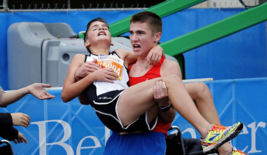 Trace Greer, right, carries his brother Judson Greer after they crossed the finish line together in the half marathon during the MetroPCS Dallas Marathon Sunday, Dec. 14, 2014 in Dallas, Texas. (AP Photo/The Dallas Morning News, G.J. McCarthy)