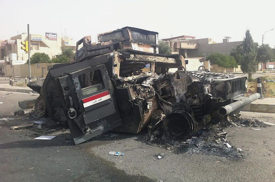 FILE - In this Thursday, June 12, 2014 file photo, an Iraqi army armored vehicle is seen burned on a street of the northern city of Mosul, Iraq. Iraqi Prime Minister Haider al-Abadi announced last month that at least 50,000 ghost soldiers had been identified in four different divisions of the military and cut from the military payroll. “We were paying salaries while we lack the money,” he said in a televised address. “We have started blowing some big fish out of the water and we’ll go after them until the end, even if it costs me my life and regardless of the campaigns I will be subjected to, because corruption is just as significant as terrorism."(AP Photo, File)